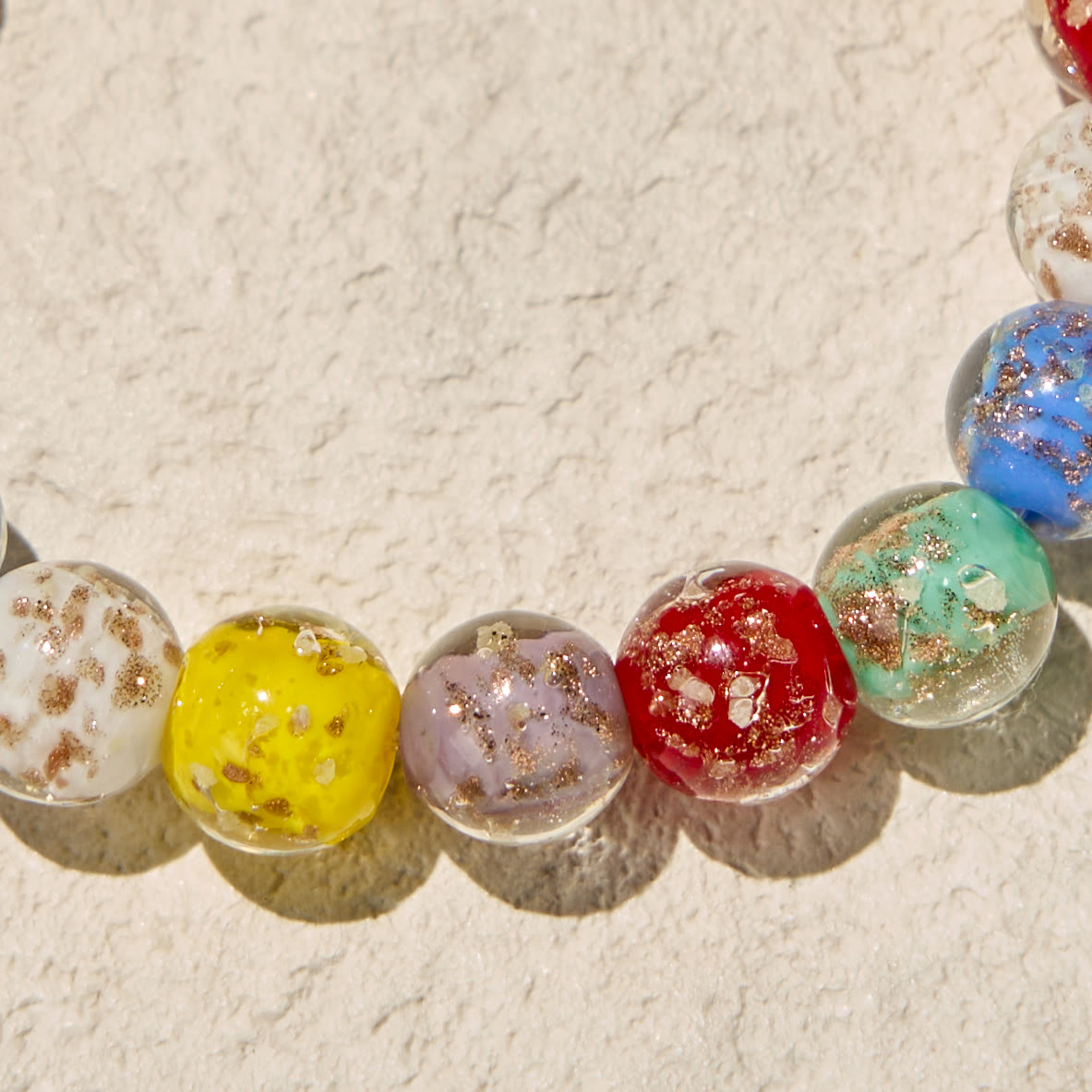 Pulseras de cristal coloridas que brillan en la oscuridad con motas doradas y crucifijo