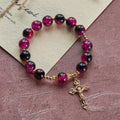 Pulsera Grace and Strength de cuentas de cristal negras y rosas con cruz dorada